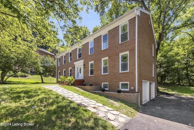 view of front of home featuring a garage, driveway, brick siding, and a front lawn