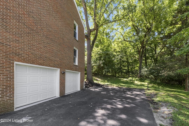 view of home's exterior with a garage, driveway, and brick siding