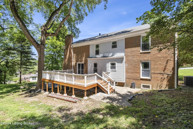 back of property featuring a lawn, a deck, central AC, and brick siding