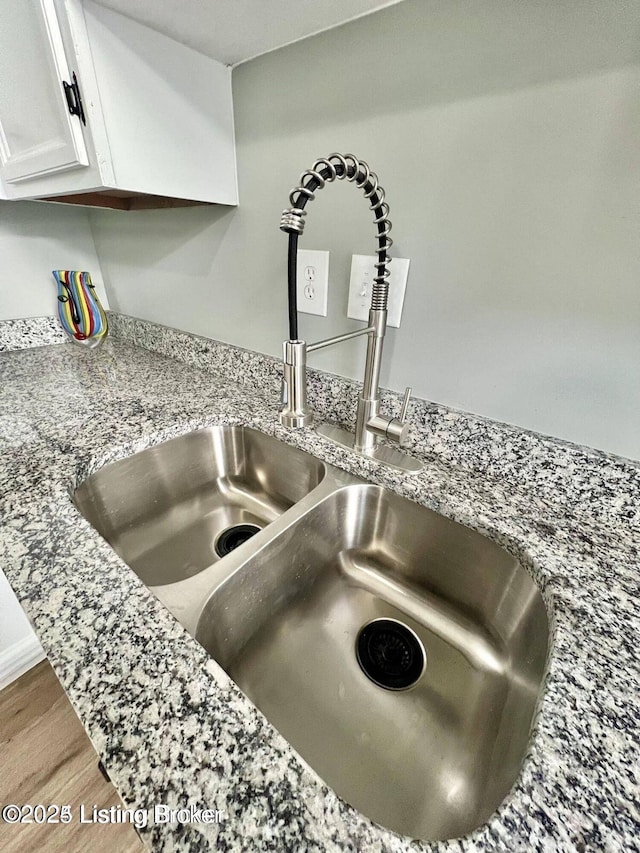 interior details with white cabinetry, a sink, and wood finished floors