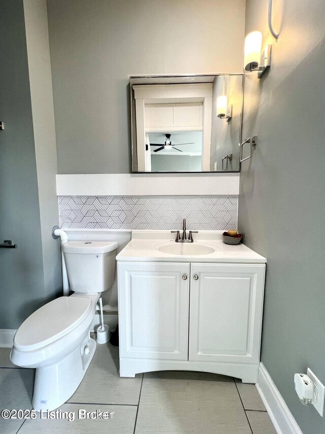 half bathroom featuring decorative backsplash, vanity, toilet, and tile patterned floors