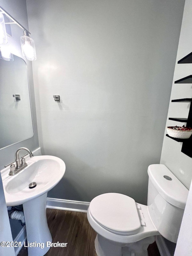 bathroom with baseboards, toilet, and wood finished floors