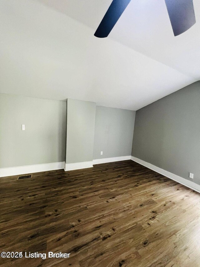 bonus room featuring lofted ceiling, visible vents, baseboards, and dark wood-style flooring