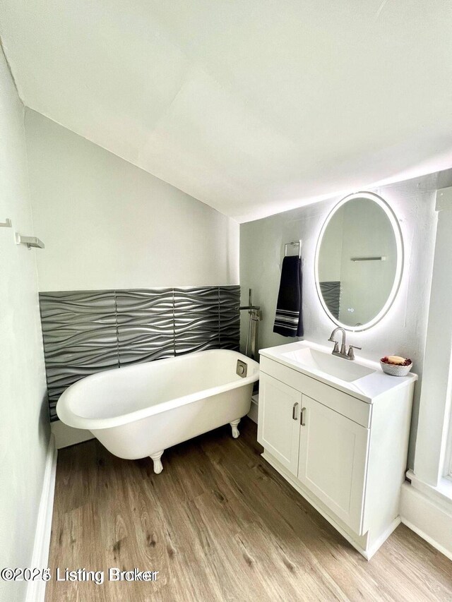 full bath with a freestanding bath, wood finished floors, and vanity