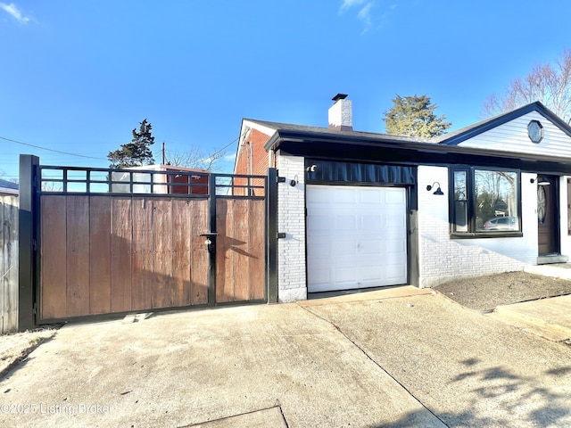 exterior space featuring brick siding, a chimney, concrete driveway, a gate, and a garage