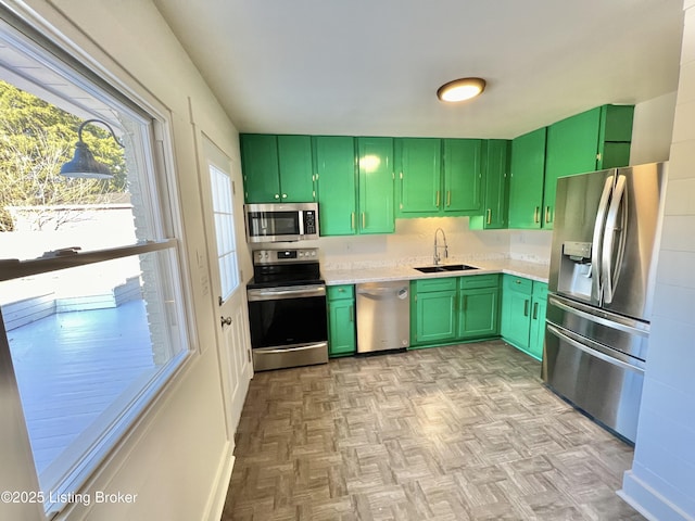 kitchen with a sink, stainless steel appliances, green cabinetry, and light countertops