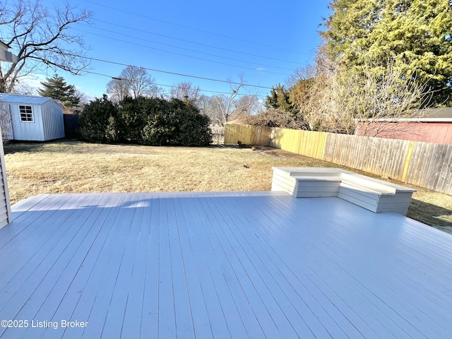 wooden deck featuring a yard, a fenced backyard, an outdoor structure, and a storage shed