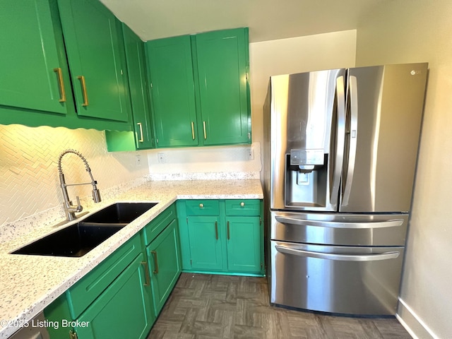 kitchen featuring tasteful backsplash, stainless steel fridge, green cabinetry, and a sink