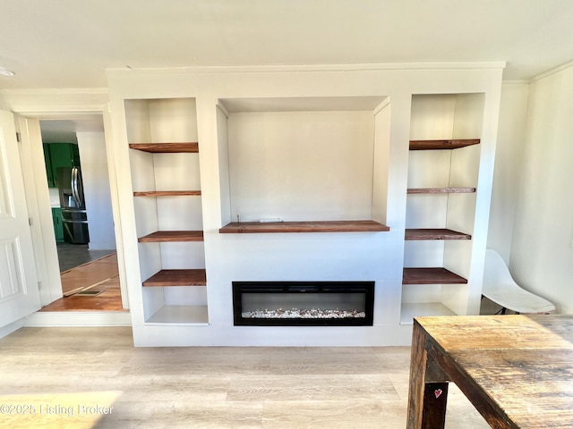 unfurnished living room with a glass covered fireplace and wood finished floors