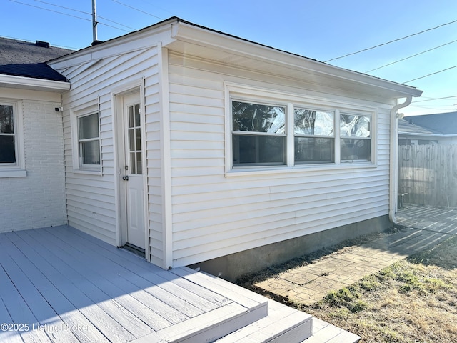 exterior space with brick siding, a wooden deck, and fence