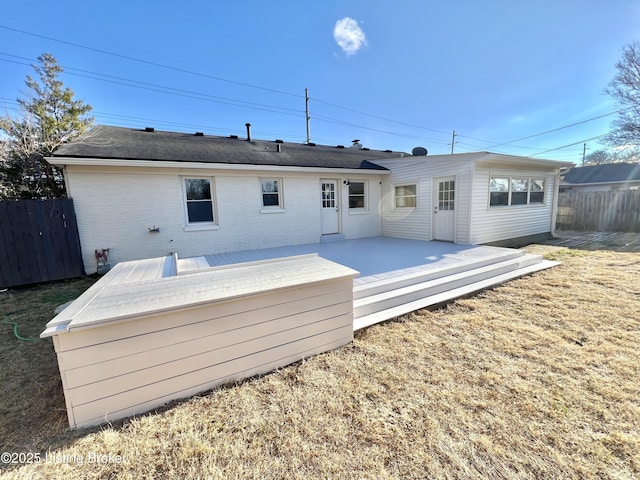 back of house with a wooden deck, fence, a lawn, and brick siding