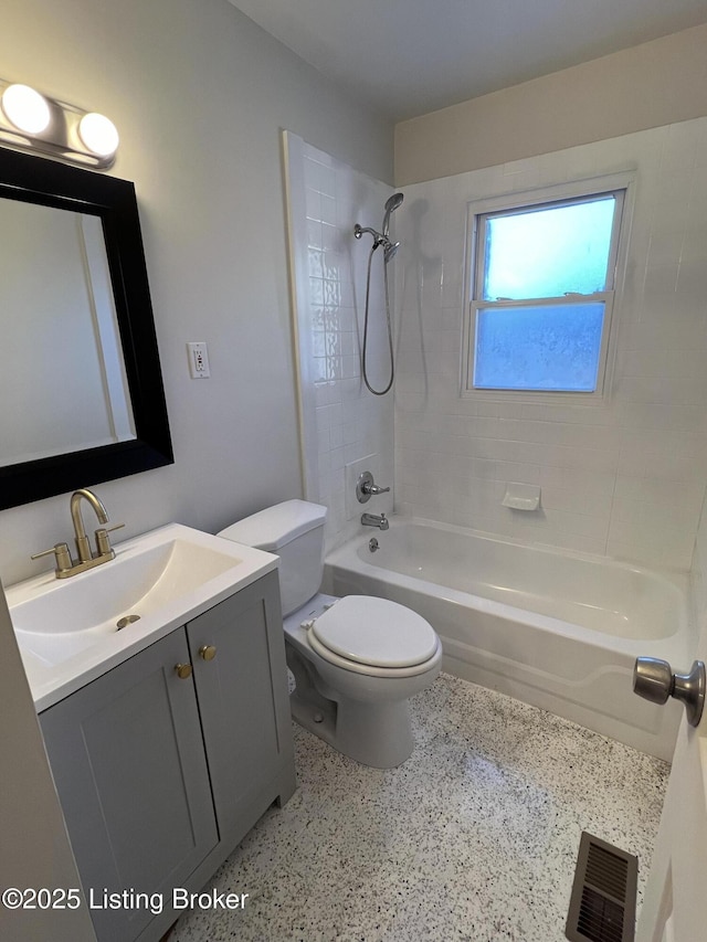 bathroom featuring visible vents, toilet, vanity, speckled floor, and shower / washtub combination