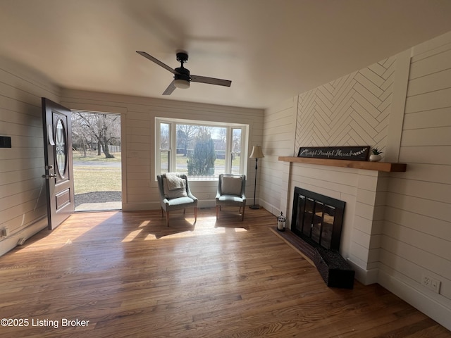 unfurnished room featuring a glass covered fireplace, wooden walls, and wood finished floors