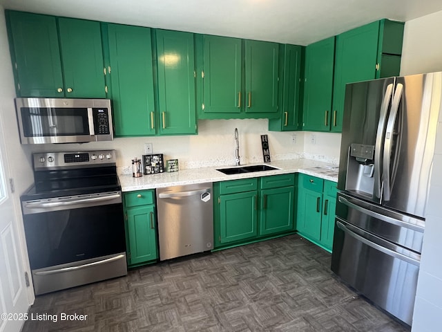 kitchen with green cabinetry, dark floors, stainless steel appliances, and a sink