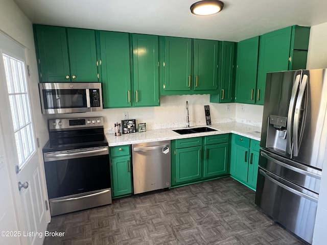 kitchen with dark floors, appliances with stainless steel finishes, a sink, and green cabinetry