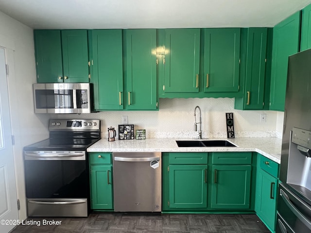 kitchen featuring green cabinets, light countertops, appliances with stainless steel finishes, and a sink