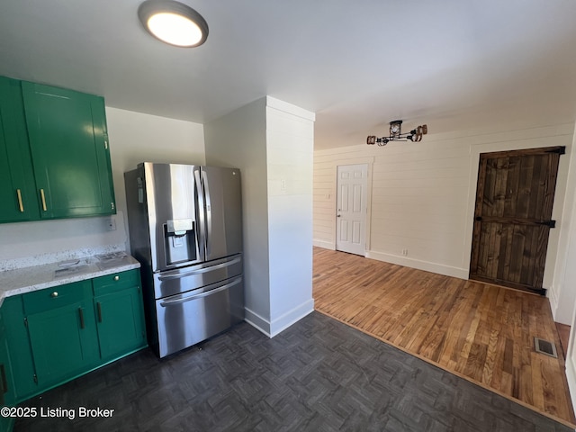 kitchen with visible vents, green cabinets, light countertops, parquet floors, and stainless steel fridge with ice dispenser