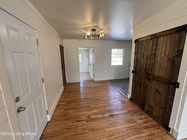 corridor with a notable chandelier, baseboards, and wood finished floors