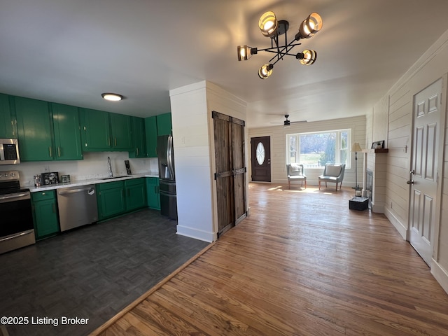 kitchen with dark wood-style flooring, stainless steel appliances, light countertops, green cabinets, and a sink