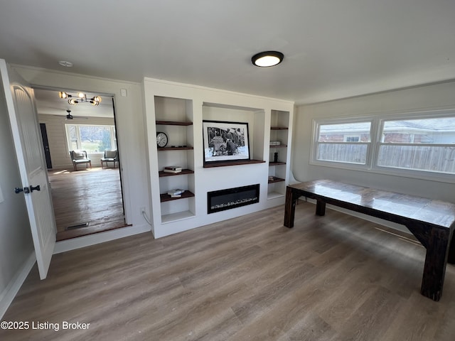 sitting room featuring a glass covered fireplace, wood finished floors, and built in shelves