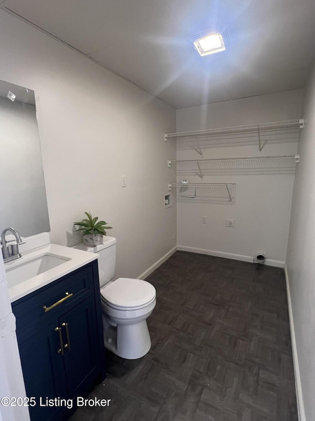 bathroom with toilet, vanity, and baseboards