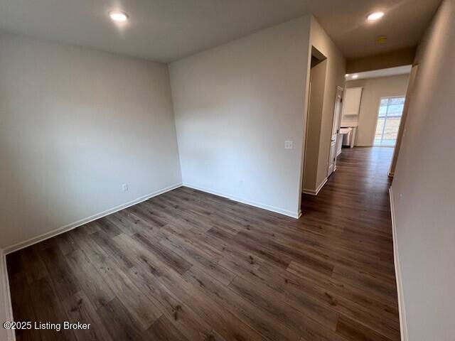 spare room with baseboards, dark wood finished floors, and recessed lighting