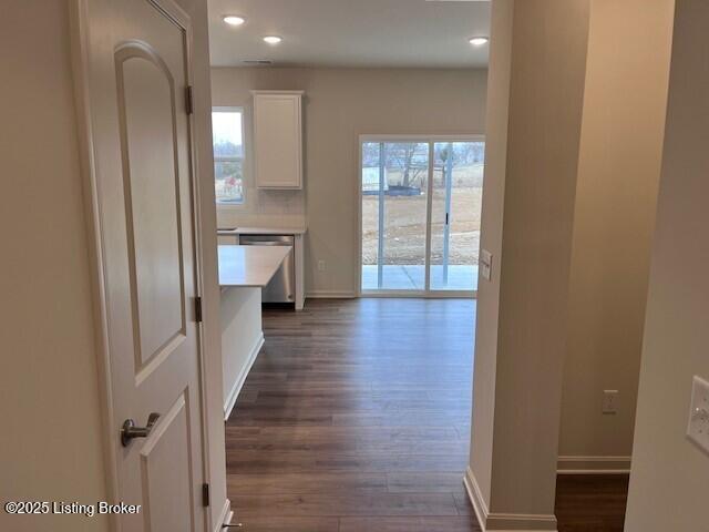 hallway with a healthy amount of sunlight, baseboards, dark wood finished floors, and recessed lighting