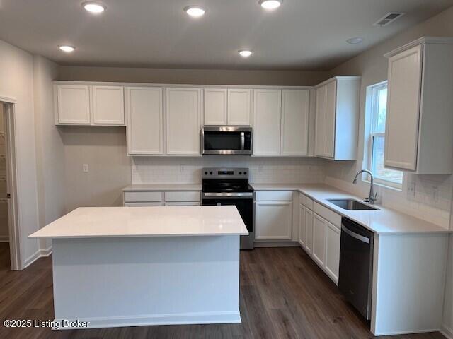 kitchen featuring a center island, visible vents, appliances with stainless steel finishes, white cabinets, and a sink