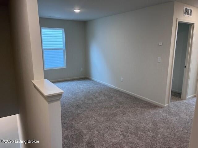 spare room featuring carpet floors, visible vents, and baseboards