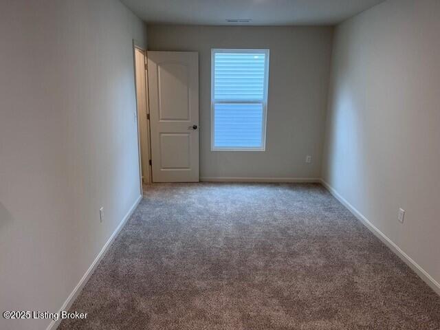 unfurnished room with carpet, visible vents, and baseboards