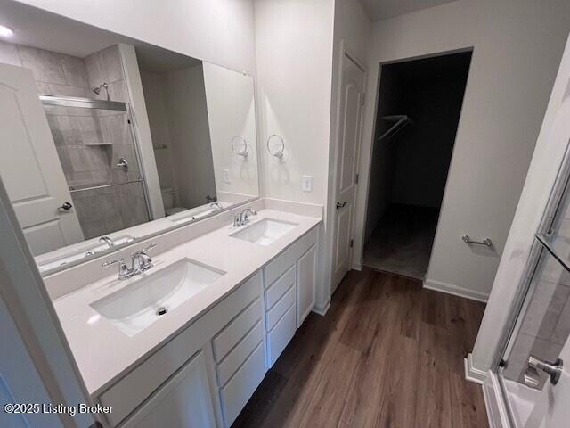 full bathroom featuring toilet, a stall shower, a sink, and wood finished floors