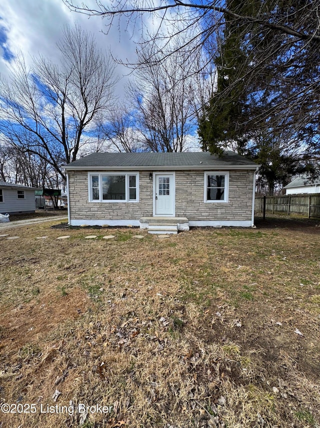 view of front facade with a front yard, stone siding, fence, and entry steps