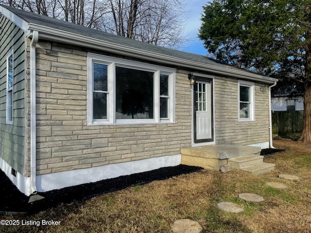 exterior space featuring stone siding and fence