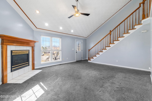 unfurnished living room featuring baseboards, a ceiling fan, a tile fireplace, stairs, and carpet floors