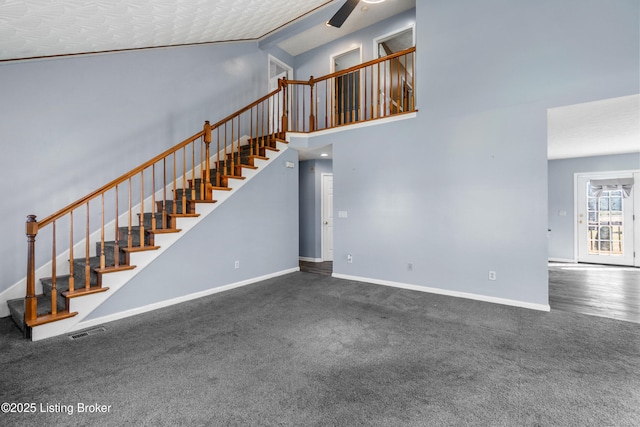 unfurnished living room featuring high vaulted ceiling, a ceiling fan, visible vents, stairs, and baseboards