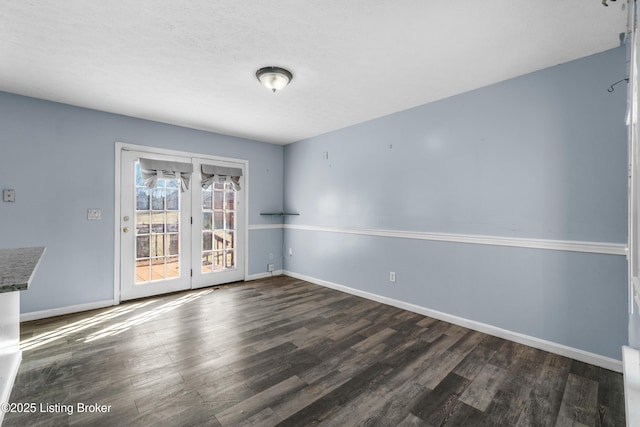 empty room featuring baseboards and dark wood finished floors