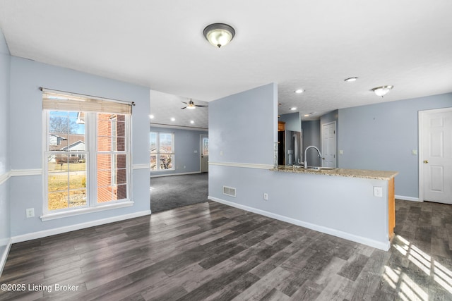 unfurnished living room featuring recessed lighting, a sink, visible vents, baseboards, and dark wood-style floors