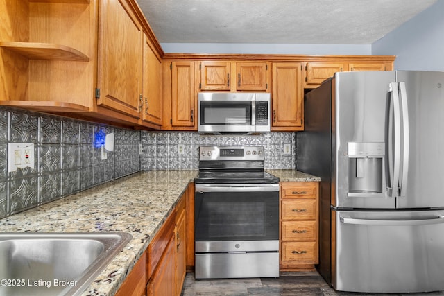 kitchen with open shelves, stainless steel appliances, tasteful backsplash, brown cabinetry, and a textured ceiling