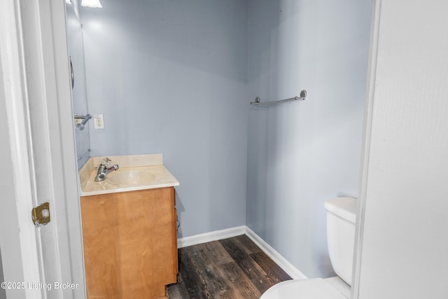 bathroom with baseboards, vanity, toilet, and wood finished floors