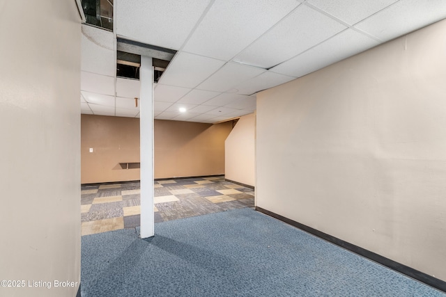 finished basement featuring a paneled ceiling, carpet, and baseboards