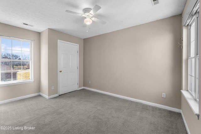 unfurnished bedroom featuring a textured ceiling, carpet flooring, visible vents, and baseboards