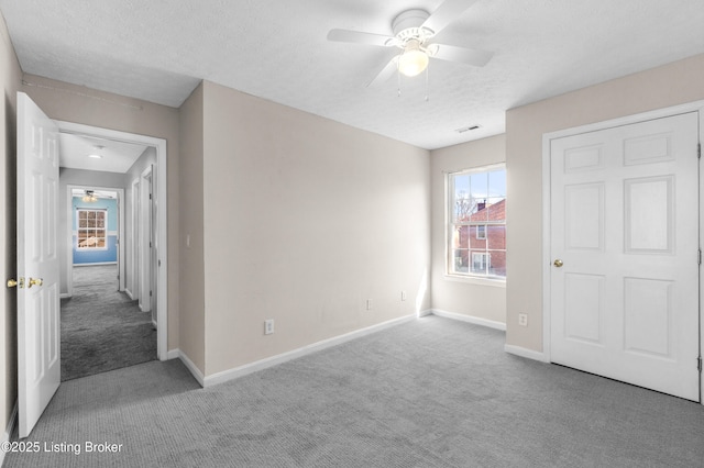 unfurnished bedroom featuring a textured ceiling, carpet flooring, visible vents, and baseboards