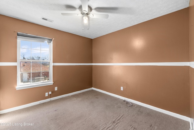 carpeted empty room with visible vents, ceiling fan, a textured ceiling, and baseboards