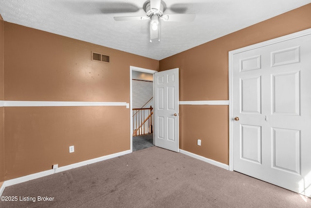 unfurnished bedroom featuring a textured ceiling, carpet floors, visible vents, and baseboards