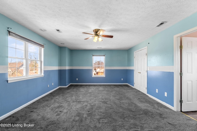 spare room with visible vents, dark carpet, ceiling fan, a textured ceiling, and baseboards