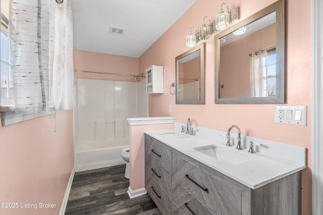 bathroom with toilet, wood finished floors, a sink, and visible vents