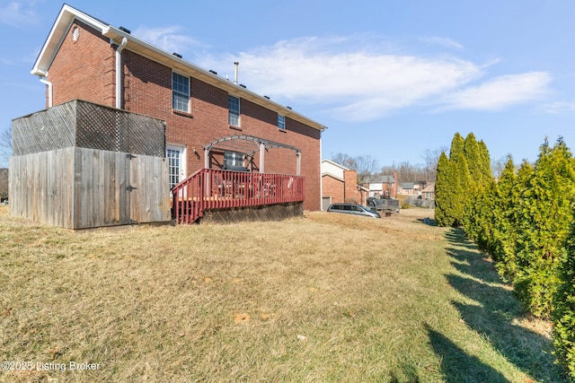 rear view of property featuring an outbuilding, a deck, a yard, a pergola, and brick siding