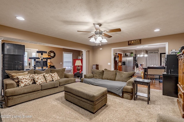 living area featuring ceiling fan, a textured ceiling, and ornate columns