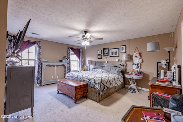 bedroom with ceiling fan, a textured ceiling, carpet flooring, and visible vents