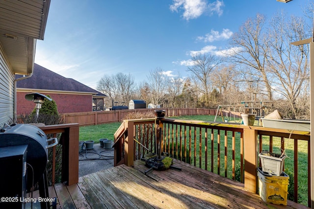 wooden deck with a fenced backyard, a playground, a grill, and a lawn